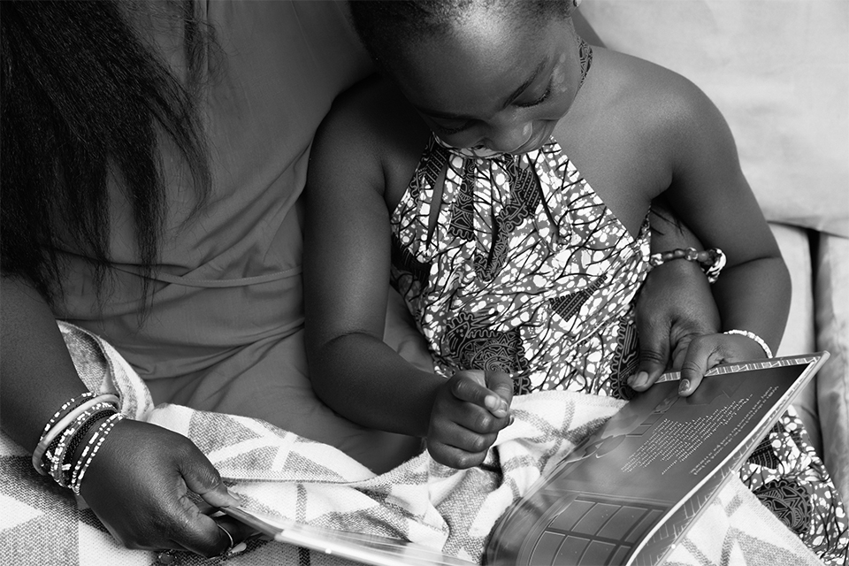 Young girl reading a book in an adult's lap