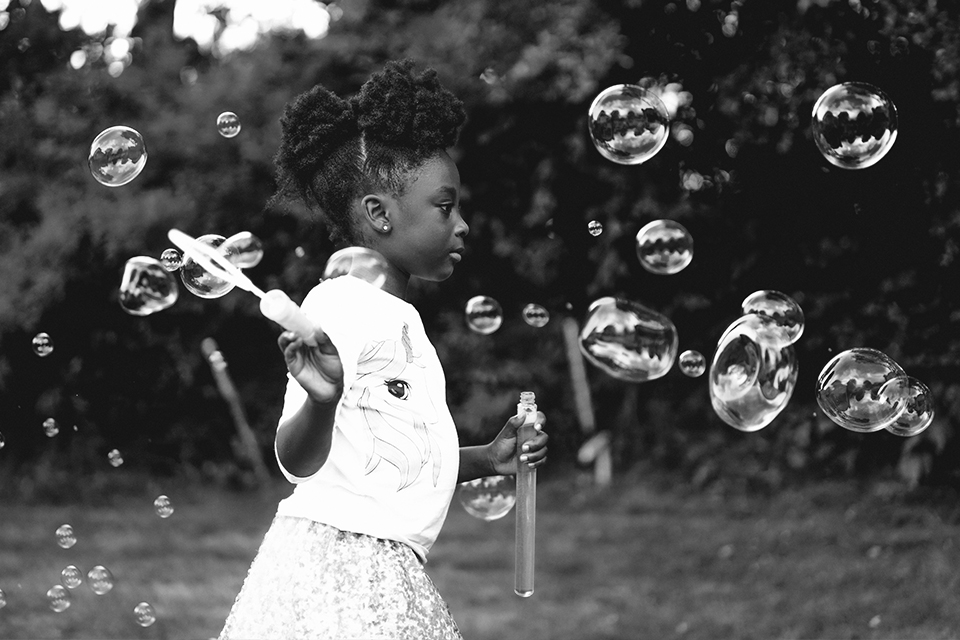 Black and white photo of young girl playing with bubbles
