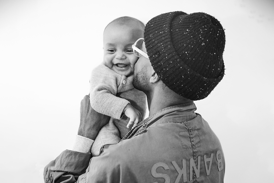 Man holding and kissing a babies cheek.