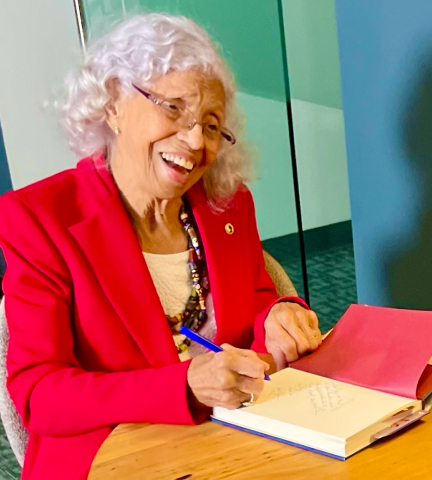 Josie R Johnson signing a book.